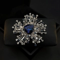 Detailed close-up of a silver brooch with a deep blue triangle crystal and clear rhinestones - Blue Retro Floral