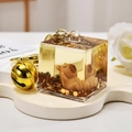 Macro shot of liquid glitter keychain with brown cartoon capybara and gold bell detail - Liquid Sand Capybara-Lying Back