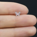 Dettaglio macro di un orecchino a farfalla in argento con pietra rosa sul dito - Farfalla in Zircone Rosa