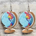 Detailed view of handmade globe earrings with wooden base on light stone wall background - Globe Style