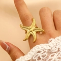 Gold starfish ring in stainless steel worn on hand with white lace sleeve detail - 18k Gold Large Starfish Style (WG-1143)