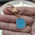 Blue enamel smiley face keychain with gold plated alloy finish on a palm view - Large Single Blue
