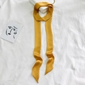 Dettaglio di un elegante nastro di seta giallo annodato al manico di una borsa bianca - 200cm / Giallo Zenzero