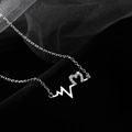 Collier vague de battement de coeur en argent avec pendentif coeur diamanté sur fond noir - Collier Battement de Coeur - Or Blanc