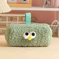 Detail of mint green plush pencil case with cartoon eyes on a pink desk setup - Green