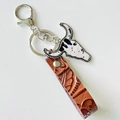 Close-up of Western style leather keychain featuring a vintage bull head pendant and texture - Brown Embossed Strap + Black White Cow Print Bull Head