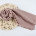 Chiffon hijab wrap in dusty rose color displayed on a natural woven straw mat - 110