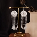 Close-up of Bohemian silver tassel earrings with geometric discs on a display stand - Vintage Disc Cone Pendant Style E4413