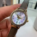 Quartz watch with mother of pearl dial and grey leather strap held by hand - Khaki