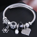 Elegant silver twisted wire charm bracelet with black floral beads and a heart pendant - Black