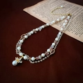 Detalle de collar de doble capa con perlas barrocas, piedras rosas y colgante de flor - Collar de Doble Capa de Perlas y Cristal Dorado