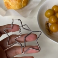 Detailweergave van zilveren stervormige oorringen in de hand voor de afmetingen - Zilveren Pin Zilver (6 CM)