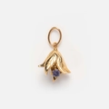Nahaufnahme eines goldenen Blumenanhängers mit lila Edelstein auf weißem Grund - Dezember Stechpalme Anhänger