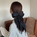 Detalle del lazo grande de satén negro para el cabello usado por una modelo en un hogar - Negro