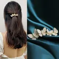 Golden butterfly hair clip with white pearls on a dark green silk background - Flowing Butterfly Pearl Spring Clip