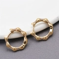 Close-up van gouden oorringen met regenboog strass-steentjes op een keramische schaal - Gouden Hoop Oorbellen met Strass