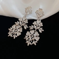 Detail shot of cascading hollow silver flower earrings on elegant black and white silk - Hollow Flower Cascading Tassel (Silver Needle) / Silver
