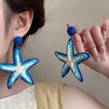 Close-up of oversized raffia woven starfish earrings in blue and white bohemian style - 17# Steel Pin - Blue