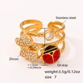 Dettaglio anello in acciaio inossidabile dorato 18k con farfalla in zircone e coccinella - US 7 / Anello Insetto Oro (A754)