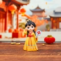Q-style girl figurine in yellow Hanfu holding a floral fan on a wooden surface - Fuguang