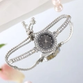 Detalle de reloj plateado para mujer con esfera floral sobre superficie reflectante - Negro