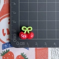 Detailed close-up of 1.5cm mini resin red cherry with bow print on measuring mat - Cherry with Left Bow Print