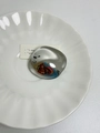Gros plan d'une broche géométrique argentée irrégulière sur une assiette en porcelaine blanche - Style Disque Argenté (Y-220)