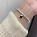 French vintage style silver beaded bracelet with a black heart charm on female wrist - Heart Bracelet