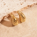 Eleganti orecchini a goccia dorati con texture ondulata su sfondo in pietra neutra - goccia / Goccia d'Acqua Oro