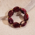 Detalle de cuentas de acrílico jaspeado rojo oscuro y anillos dorados en la pulsera de moda - Rojo