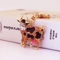Cute cow keychain with colorful crystals and gold-plated finish on minimalist book background - Brown