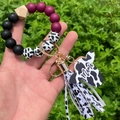 Detail of mama cow head charm with leopard beads and tassel keychain on wrist - Purple/Cow Print