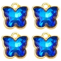Macro view of four sapphire blue crystal butterfly charms with gold alloy edging - Sapphire Blue