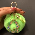 Detailed close-up of a bright green fluffy pompom keychain with a clear resin letter Q charm - Letter Q