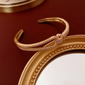 Close-up of golden knot bracelet with sparkling zircon stones on a luxury mirror base - Gold