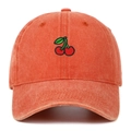 Close-up of cherry embroidery and vintage washed cotton texture on an orange baseball cap - Orange