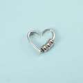Detail of silver heart-shaped earring with textured beads on a light blue background - Steel Heart Pendant