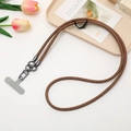 Detail of brown braided phone lanyard with dark grey metal clasp on elegant background - Coffee