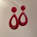 Close-up of elegant burgundy resin teardrop earrings hanging on a transparent stand - Burgundy Hollow Teardrop Style (Silver Pin)