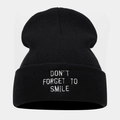 Detail of embroidered 'DON'T FORGET TO SMILE' slogan on black knit beanie cuff - Black