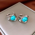 Detail view of round turquoise earrings with silver base on a textured grey jewelry box - Silver (Silver Pin)