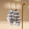 Detail of silver layered leaf tassel earrings with sparkling zircon on a gold display stand - Silver
