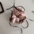 Detailed view of pink satin scrunchie featuring hanging black ribbon bows - Apricot
