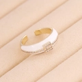 Makroaufnahme: Vergoldeter geometrischer Ring mit weißer Emaille und Zirkonia im Samtetui - Einheitsgröße(Einstellbar) / Weiß