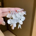 Détail macro de boucles d'oreilles fleurs élégantes avec zircons et pétales blancs - Gland de coquille en zircone étagée (17#)