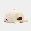 Vista detallada del gorro docker beige con bordado de oso y textura de lona - Ajustable / Beige