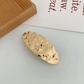 Detailed close-up of golden oval hair clip featuring a hammered metal texture finish - Oval Gold