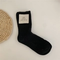 Thick black wool crew socks with a beige ribbed knit label on a white background - Black