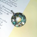 Detailansicht eines runden Anhängers aus Abalone-Muschel mit irisierendem Glanz - Runder Ring