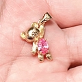 Gros plan d'un pendentif ours doré orné d'un zircon rose tenu dans la main - 2# Rose + Collier